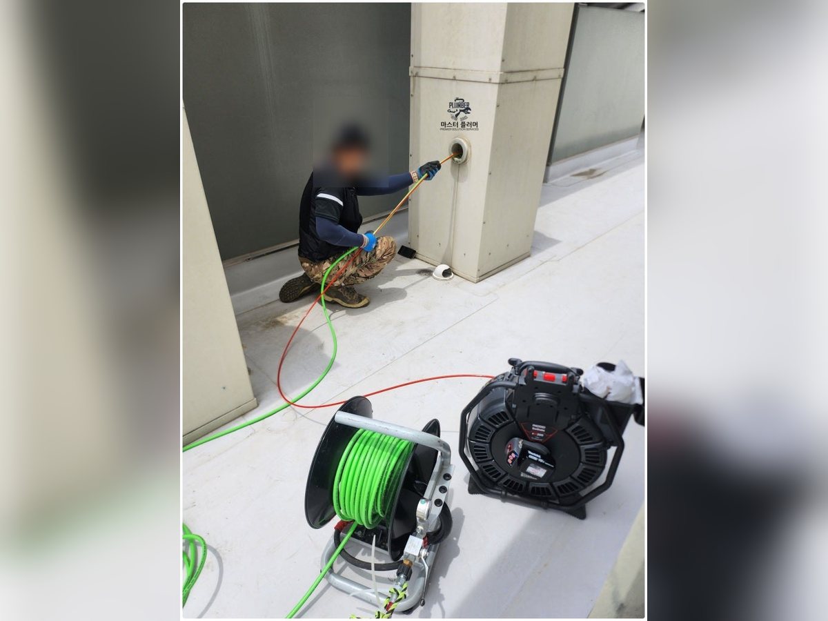 옥상 신정통기관 점검구에 세척 호스를 넣는 작업자