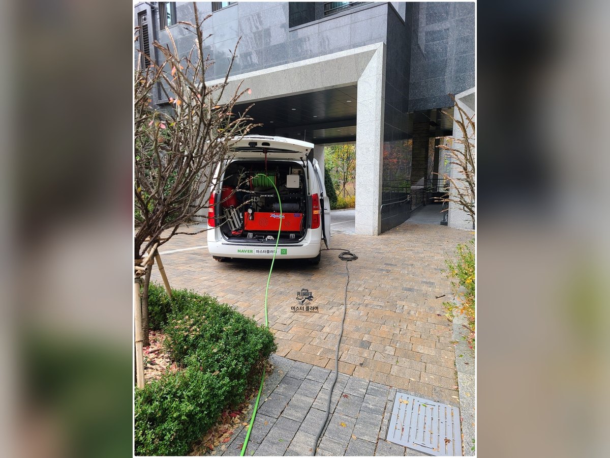 작업 차량 적재 장비에서 화단 쪽으로 호스를 연결하는 모습